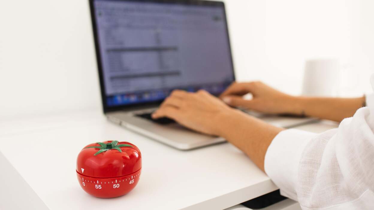 Ręka mężczyzny ustawiająca czerwony timer Pomodoro na 25 minut
