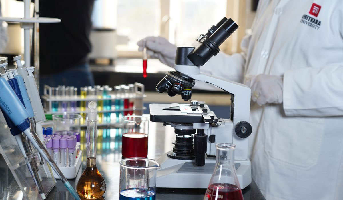 Grupa studentów w laboratorium łączy otwarte podręczniki z aparaturą eksperymentalną na stołach