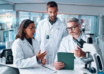 Discussion, science and tablet with people in laboratory together for breakthrough or development. Conversation, laptop and microscope with professional research team in clinical trial for discovery