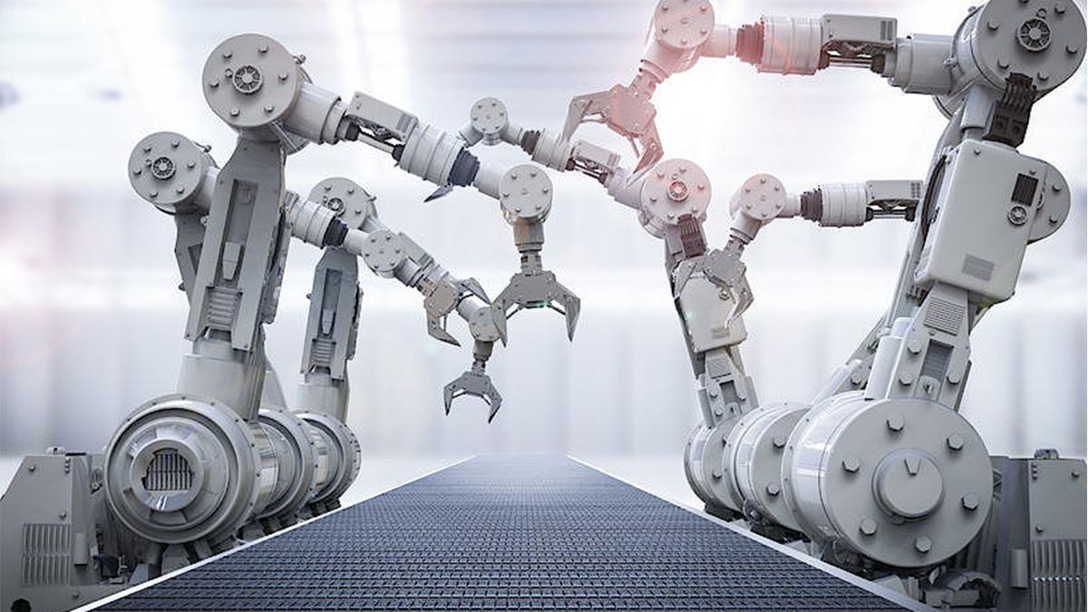 Ćwiczenia z obsługi robotów przemysłowych na uczelni student przy panelu sterowania robotem przemysłowym