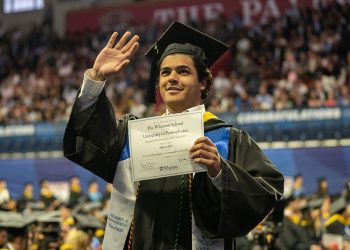 Inżynier w garniturze trzyma dyplom MBA na tle fabryki i biurowca