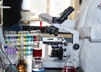 Grupa studentów w laboratorium łączy otwarte podręczniki z aparaturą eksperymentalną na stołach