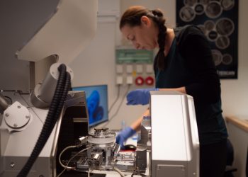 laboratorium politechniki z dużym mikroskopem elektronowym i naukowcami w kitlach