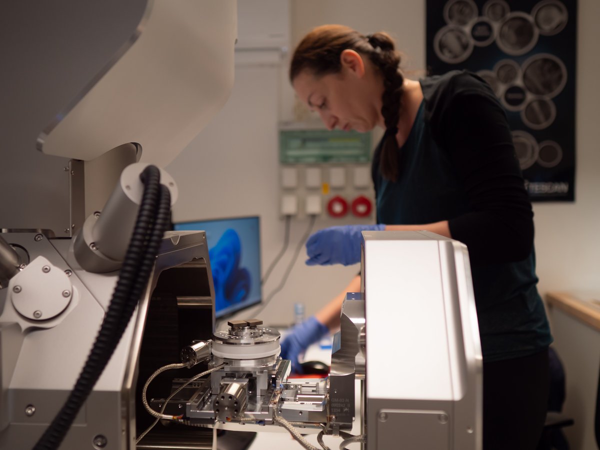 laboratorium politechniki z dużym mikroskopem elektronowym i naukowcami w kitlach