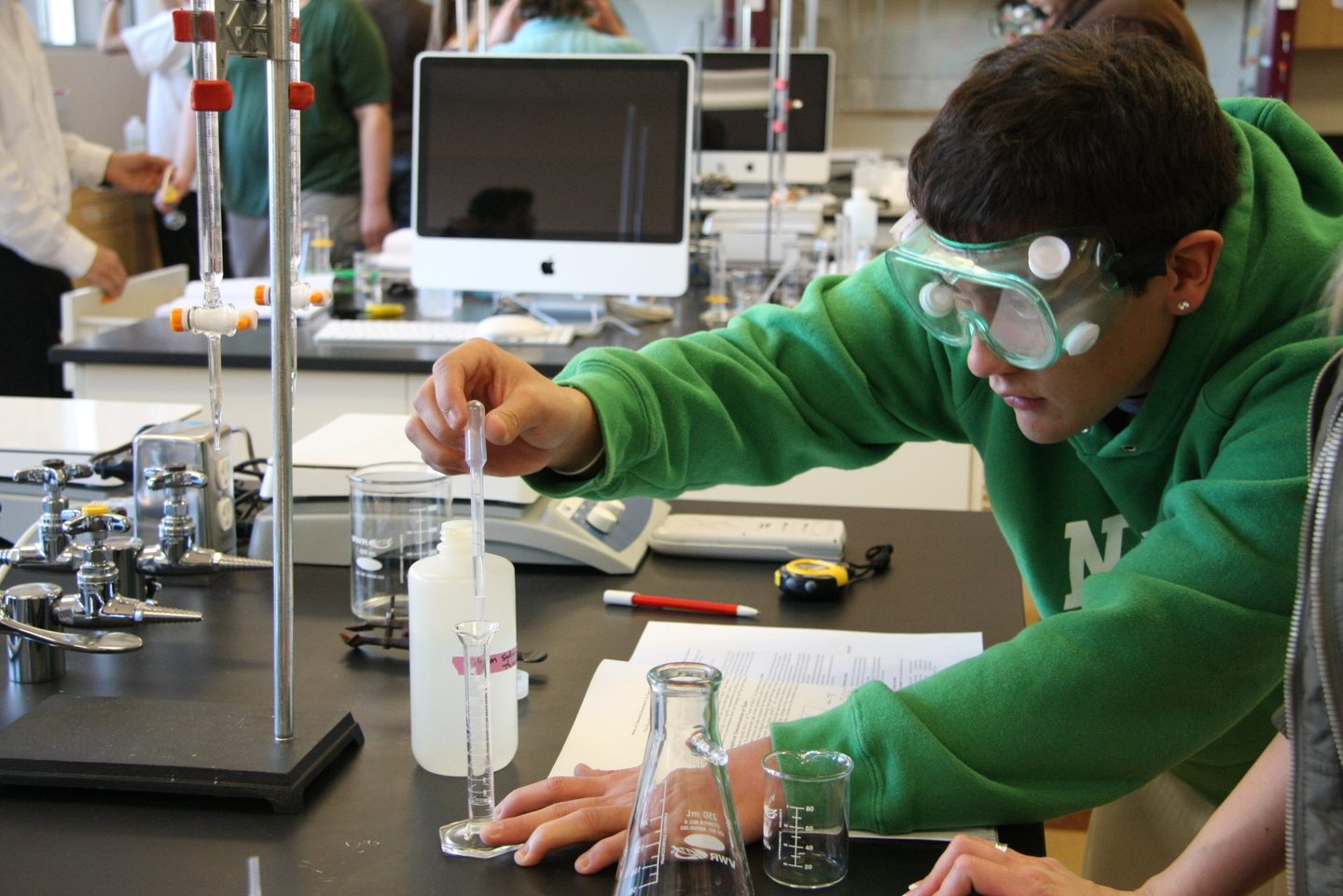 student regulujący krzesło ergonomiczne na stanowisku pracy z manekinem