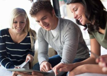 młodzi studenci w nowoczesnej sali komputerowej pracują na laptopach z ekranami pełnymi danych