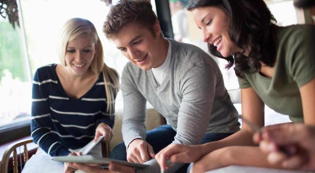 młodzi studenci w nowoczesnej sali komputerowej pracują na laptopach z ekranami pełnymi danych