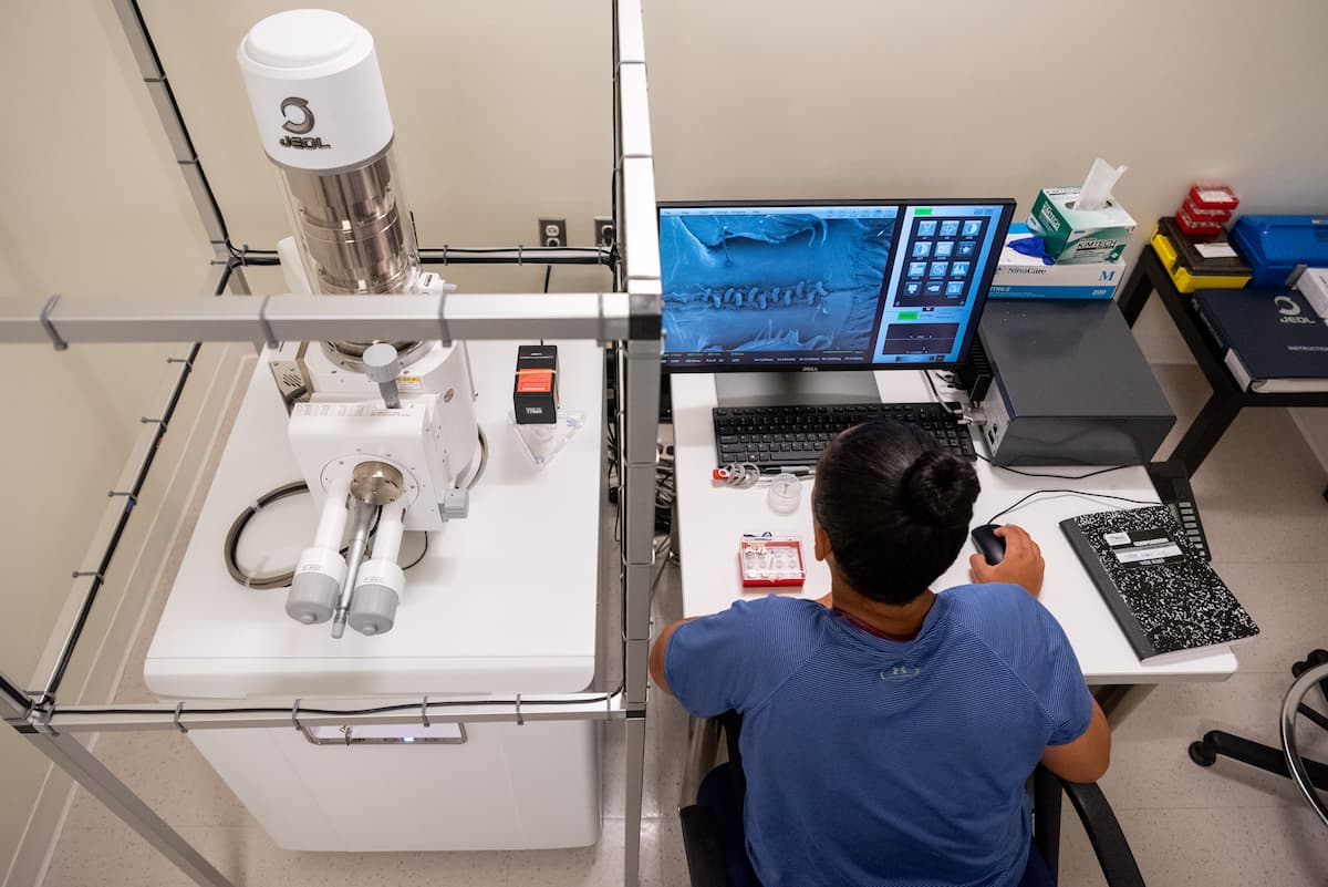 przygotowanie próbki do badania elektronowego naukowiec w białym kitle przygotowujący próbkę na podkładce do mikroskopu