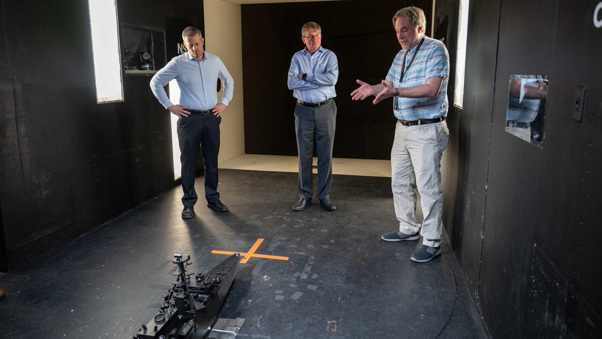 profesor wskazuje na przepływ w modelu elektrowni wodnej przed grupą studentów